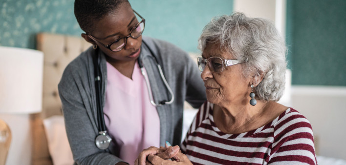 Black nurse comforts older woman