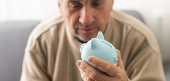 Senior caucasian man holding piggy bank with glasses depressed and worry for distress, crying angry and afraid.