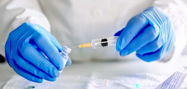 Doctor fills injection syringe with vaccine