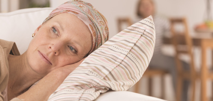 Tired woman after cancer treatment lying on couch at home