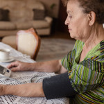 Grandmother is measuring her blood pressure on the living room