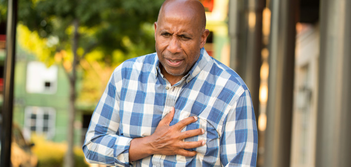African American man having pains holding his chest.