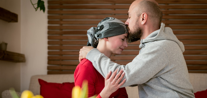 Supportive husband kissing his wife, cancer patient, after treatment in hospital.