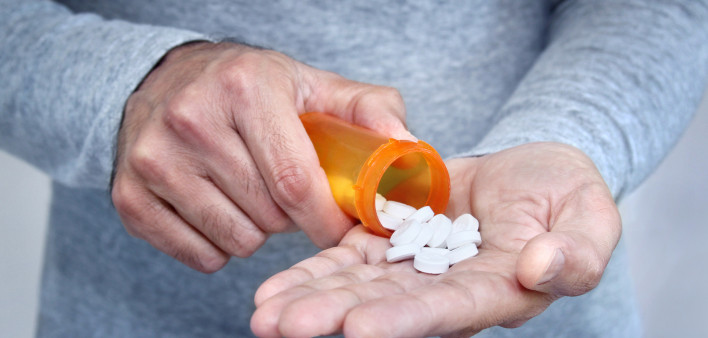 man taking pills pills in his hand