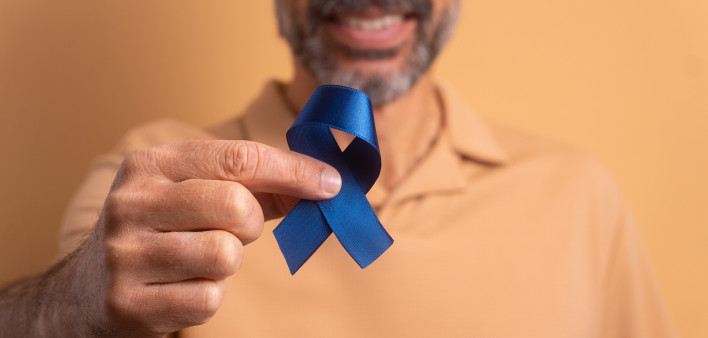 man holding blue ribbon for prostate cancer awareness