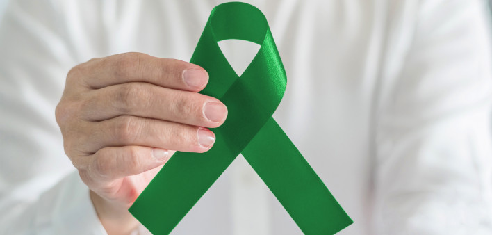 hand with green ribbon cerebral palsy and liver cancer awareness