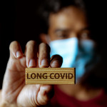 Masked Asian man show wooden sign with wording "Long Covid"
