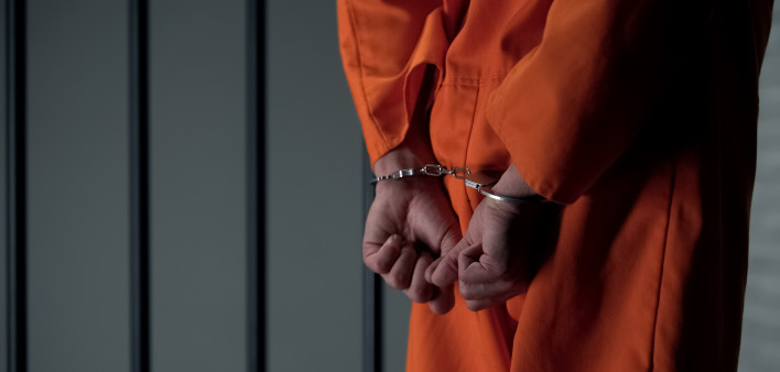 Prisoner with handcuffed arms behind back, another jail transfer, criminal
