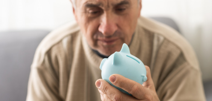 Senior caucasian man holding piggy bank with glasses depressed and worry for distress, crying angry and afraid.
