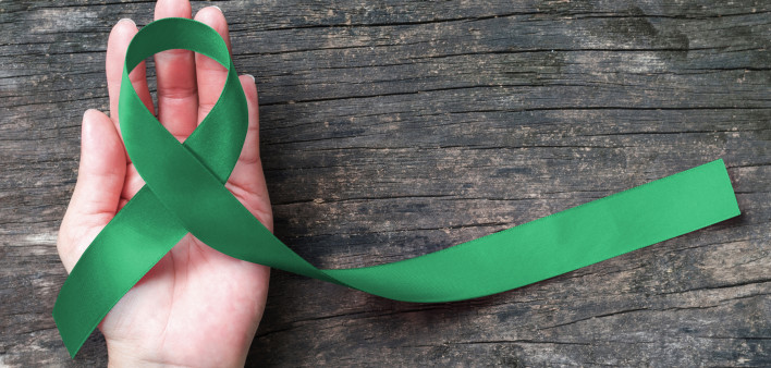 hand with green ribbon cerebral palsy and liver cancer awareness