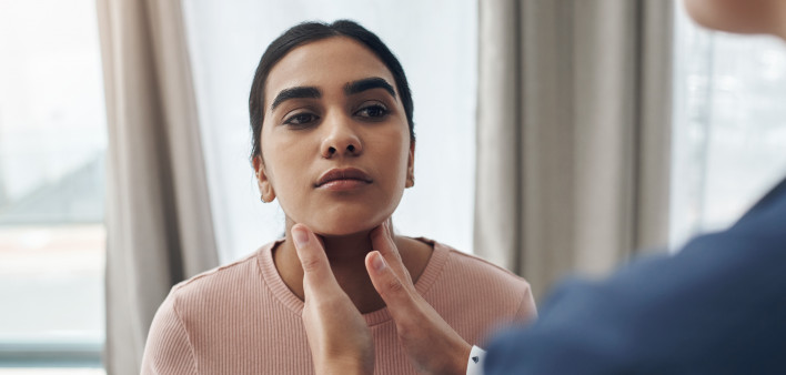 doctor checking patient’s throid gland,
