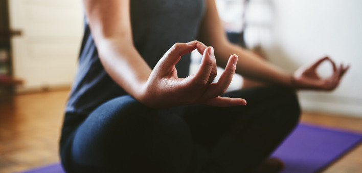 Cropped shot of an unrecognizable woman sitting on a yoga mat and meditating alone in her home