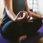 Cropped shot of an unrecognizable woman sitting on a yoga mat and meditating alone in her home