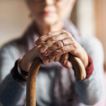 old woman, her hands resting on a cane