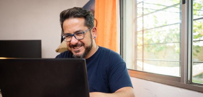 Latino man living with HIV using a laptop