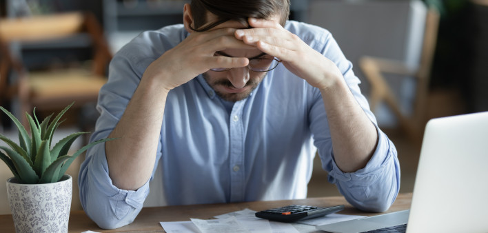 Sad depressed man checking bills, anxiety about debt or bankruptcy