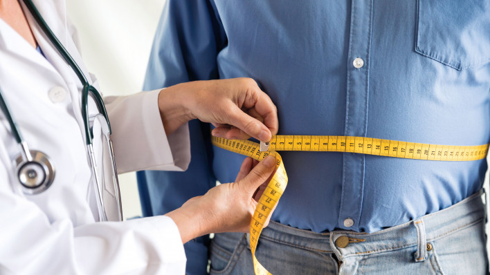 doctor measuring mans stomach