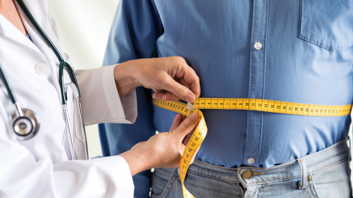doctor measuring mans stomach