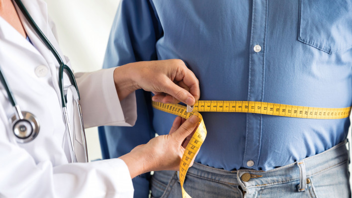 doctor measuring mans stomach