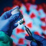 gloved hand needle vial vaccine coronavirus