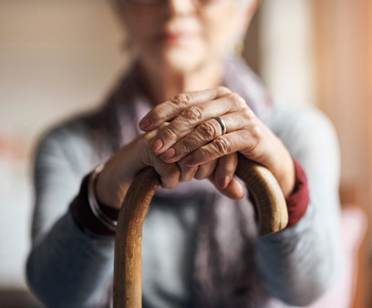 old woman, her hands resting on a cane