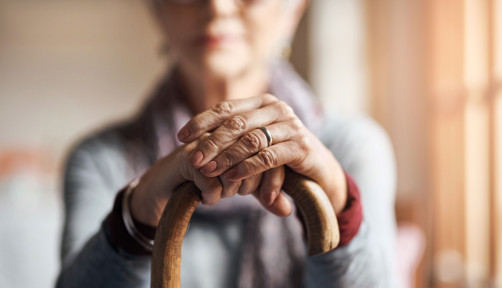 old woman, her hands resting on a cane