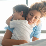 Beautiful sweet little boy hospitalized in the pediatrics ward hugging young nurse both smiling