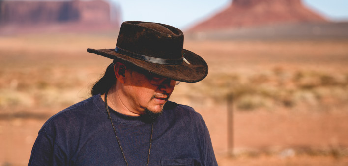 Handsome and rugged traditional Navajo Man portrait outside in Monument Valley Arizona with scenery view