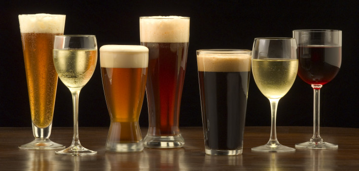 An assortment of glasses of wine and beer including a classic pilsner flute, a sparkling wine glass, an American half pint glass, a weizen or wheat beer glass, an American pint glass, a white wine glass, and a red wine glass.