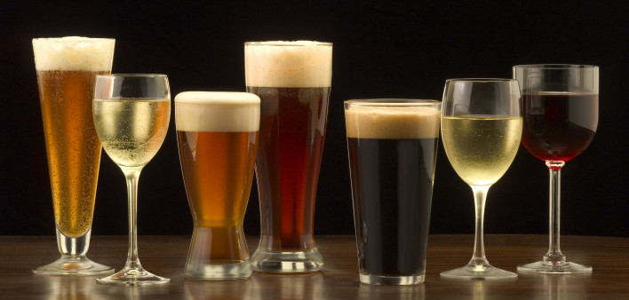 An assortment of glasses of wine and beer including a classic pilsner flute, a sparkling wine glass, an American half pint glass, a weizen or wheat beer glass, an American pint glass, a white wine glass, and a red wine glass.