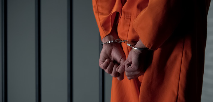 Prisoner with handcuffed arms behind back, another jail transfer, criminal