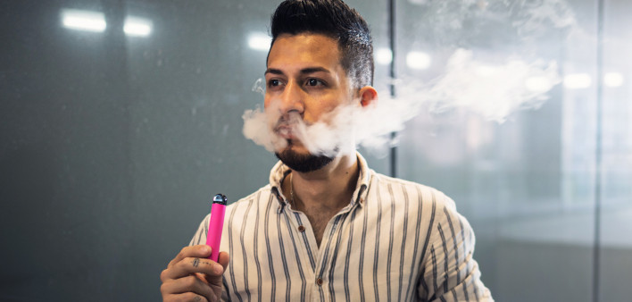 oung hispanic businessman smoking an electronic cigarette