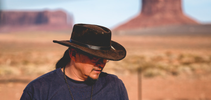 Handsome and rugged traditional Navajo Man portrait outside in Monument Valley Arizona with scenery view