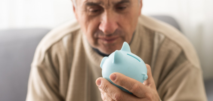 Senior caucasian man holding piggy bank with glasses depressed and worry for distress, crying angry and afraid.