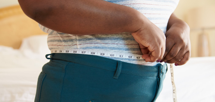 Close Up Of Overweight Woman Measuring Waist At Home Standing Still