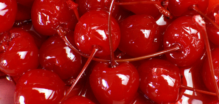 Festive background of red cocktail maraschino cherries with stems.