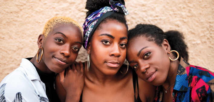 Three smiling black women hugging