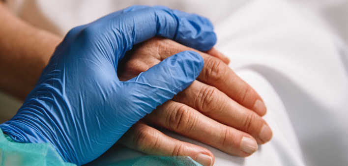 doctor hand with blue glove giving support and love to a patient at hospital. Coronavirus