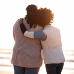 mom and daughter hugging on the beach