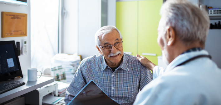 Doctor with x-rays and smiling old man patient