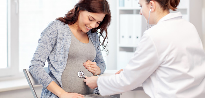 pregnancy, gynecology, medicine, health care and people concept - gynecologist doctor with stethoscope listening to pregnant woman baby heartbeat