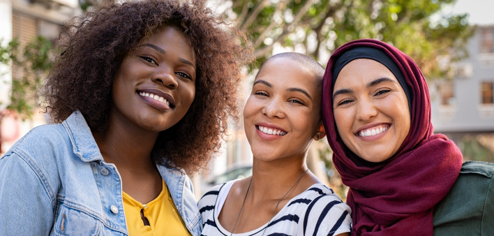 Group of three happy multiethnic friends looking at camera.
