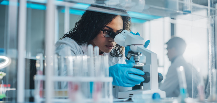 Medical Science Laboratory: Portrait of Beautiful Black Scientist Looking Under Microscope