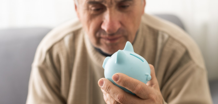 Senior caucasian man holding piggy bank with glasses depressed and worry for distress, crying angry and afraid.