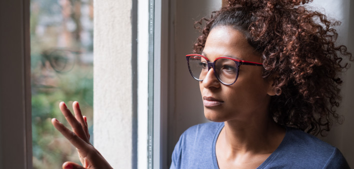 Lonely black woman near window thinking about something girl sad