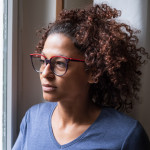 Lonely black woman near window thinking about something girl sad