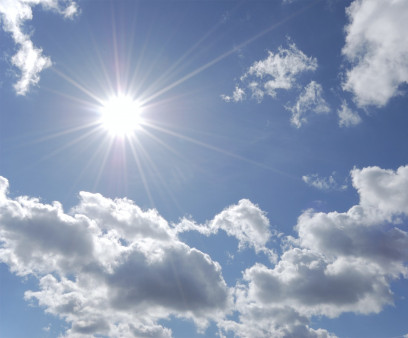 bright sun shining in blue sky with white clouds
