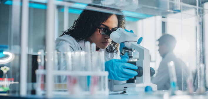 Medical Science Laboratory: Portrait of Beautiful Black Scientist Looking Under Microscope