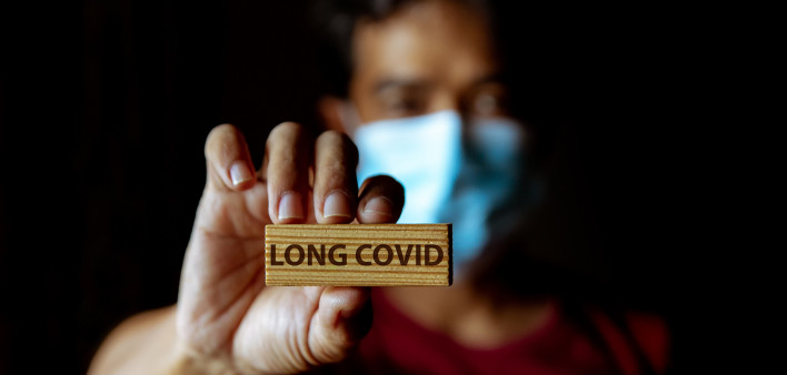 Masked Asian man show wooden sign with wording "Long Covid"
