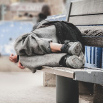 homeless man asleep on bench